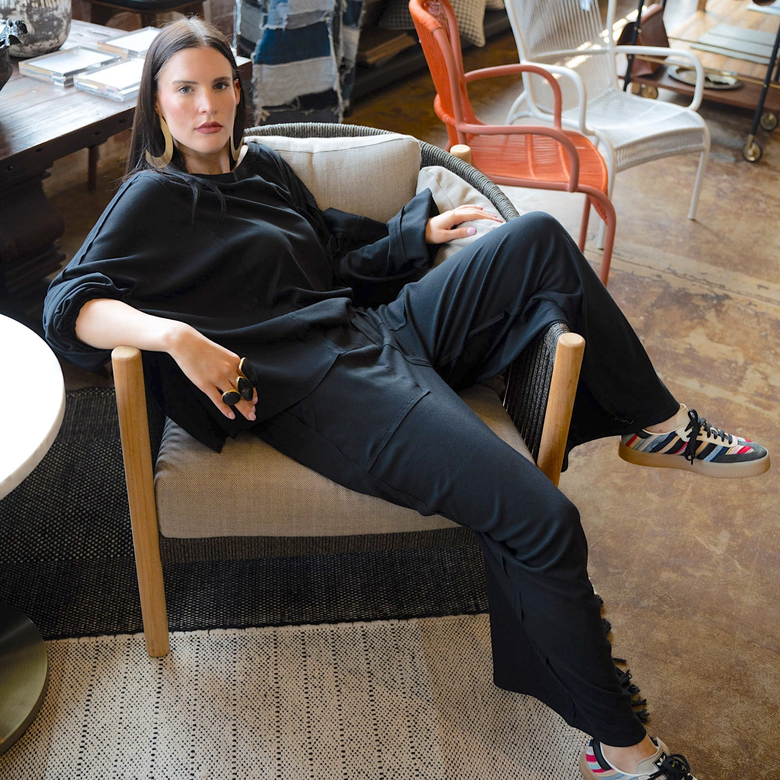 Woman sitting on a chair in a stylish room with decor elements.