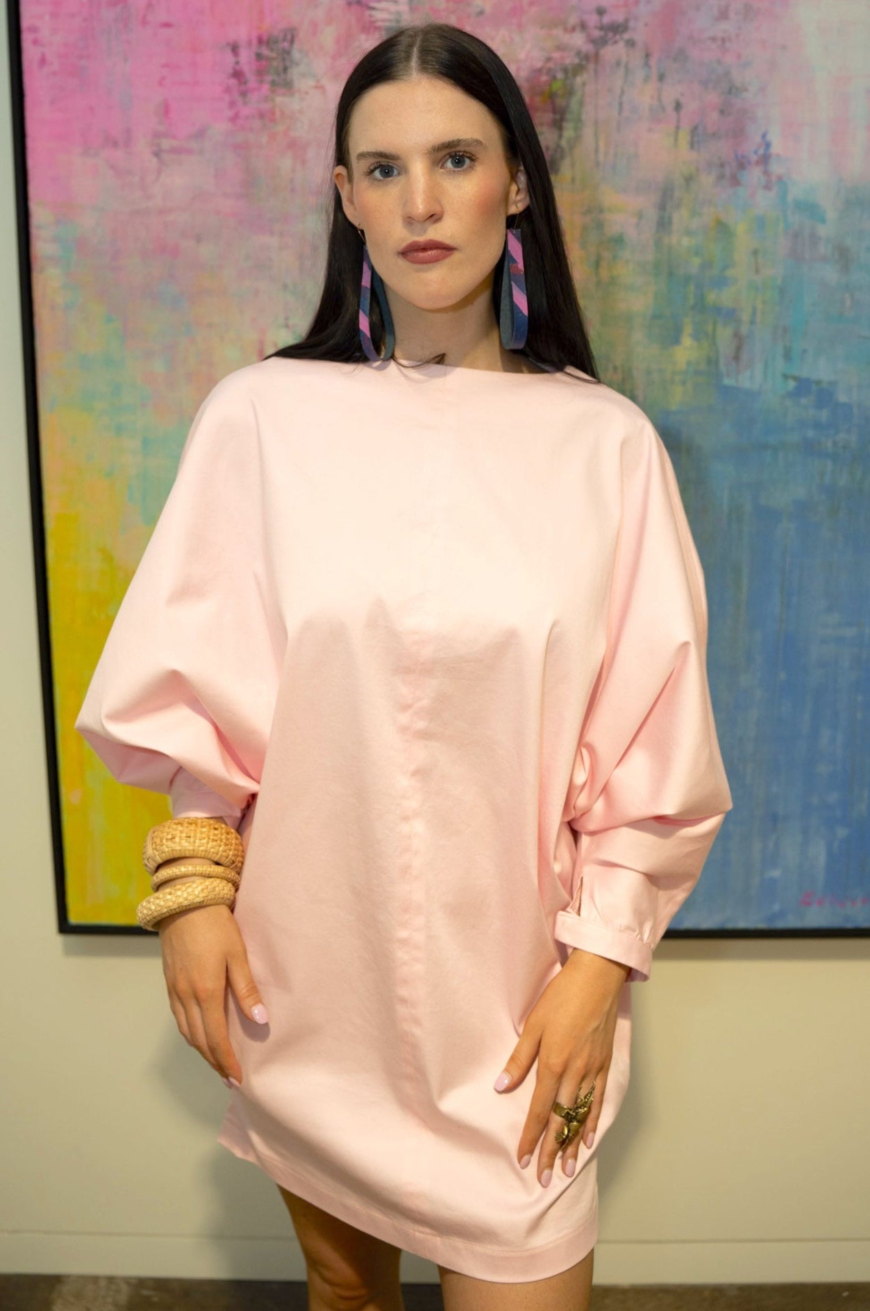Woman in a pink dress standing in front of an abstract painting