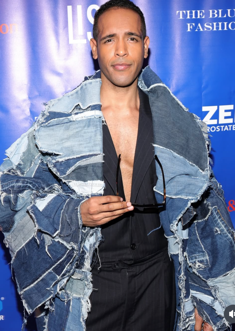 Person wearing a denim jacket on a blue background with visible branding