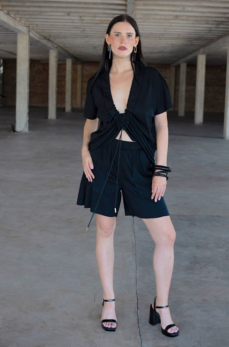 Woman in a black outfit standing in an empty concrete space.