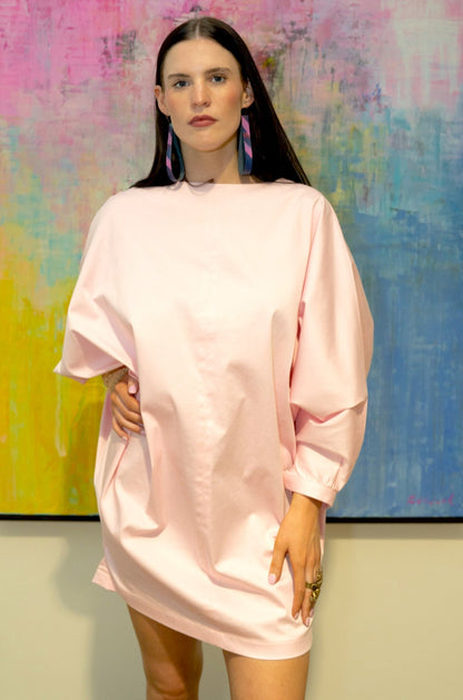 Woman wearing a pink dress standing in front of a colorful abstract painting.
