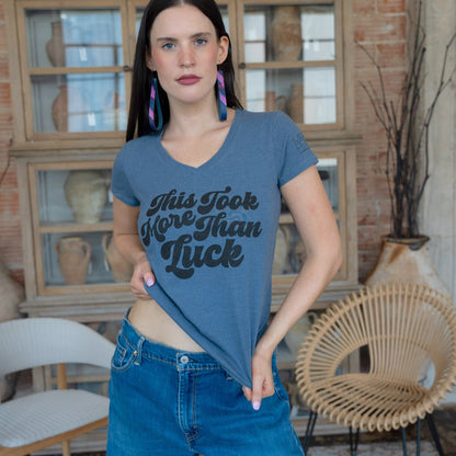 Woman wearing a blue t-shirt with text in a room with decorative vases and furniture.