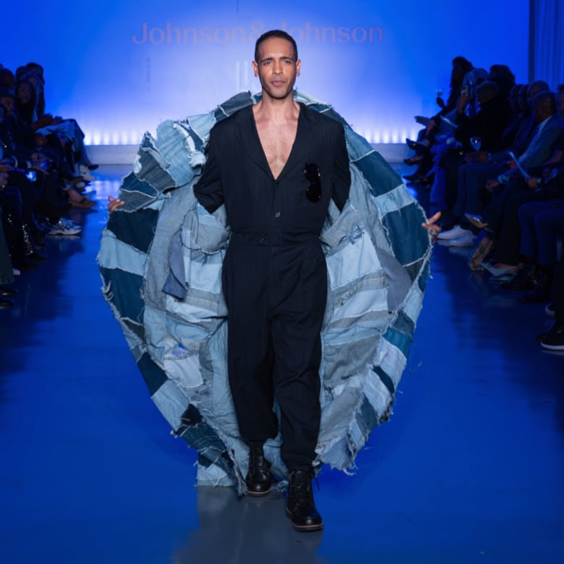 Person on a fashion show runway with a blue background and 'Louis Finley TV' branding.