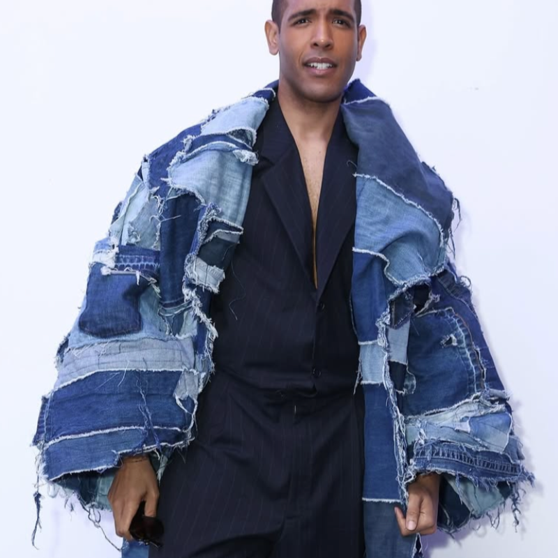 Person wearing a long blue and white denim coat against a white background