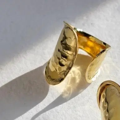 Gold cuff bracelet on a light background