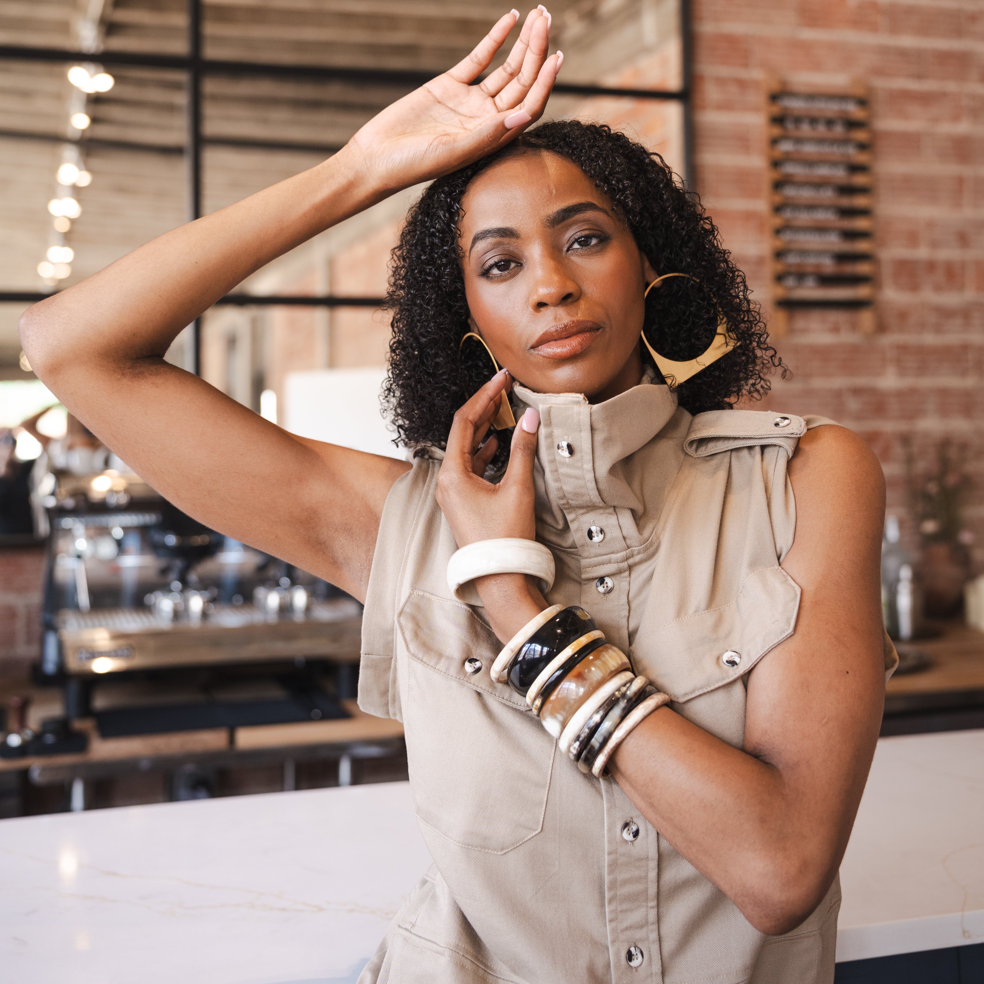 Woman in an up cycled beige sleeveless dress with jewelry in a kitchen setting