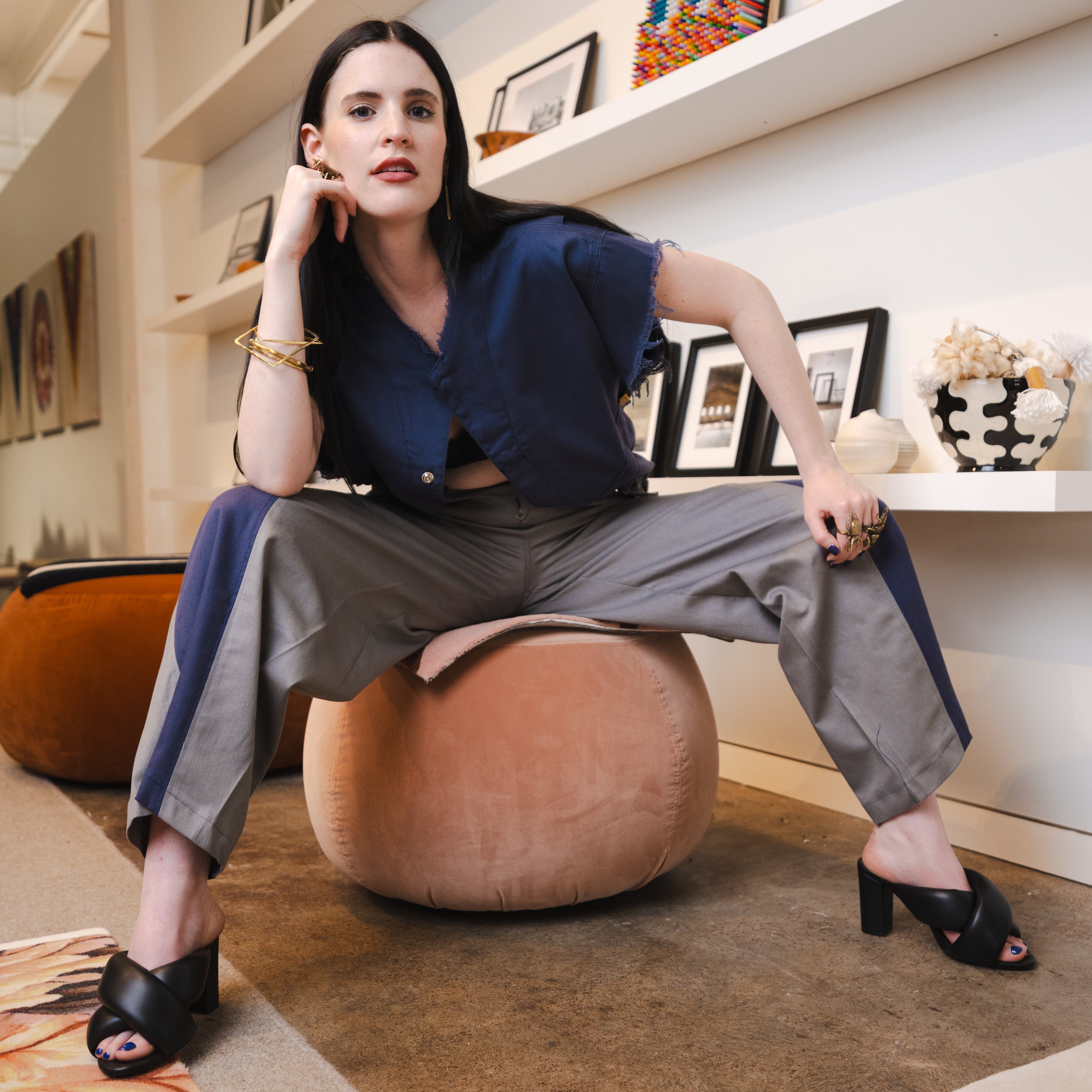 Woman sitting on a ball chair in a room with shelves and decor