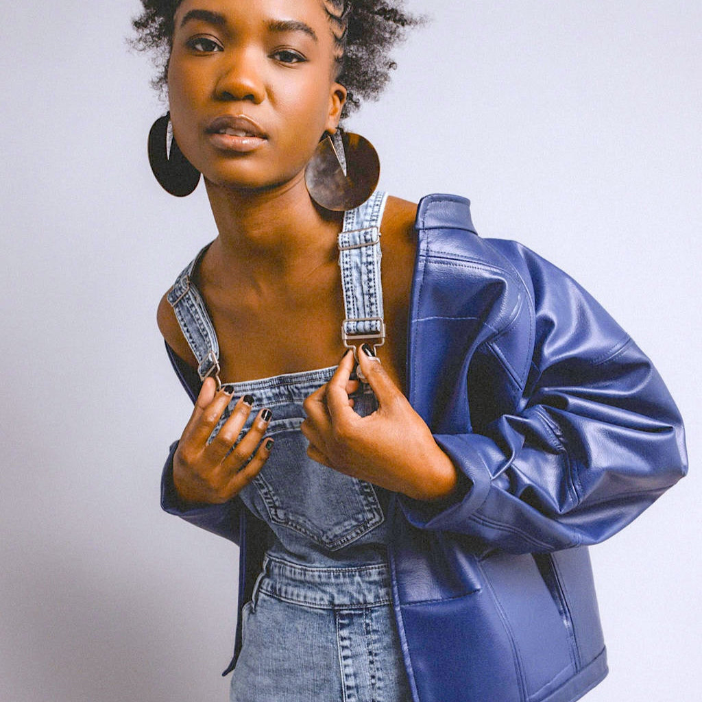 Woman wearing a denim dress and blue jacket against a plain background