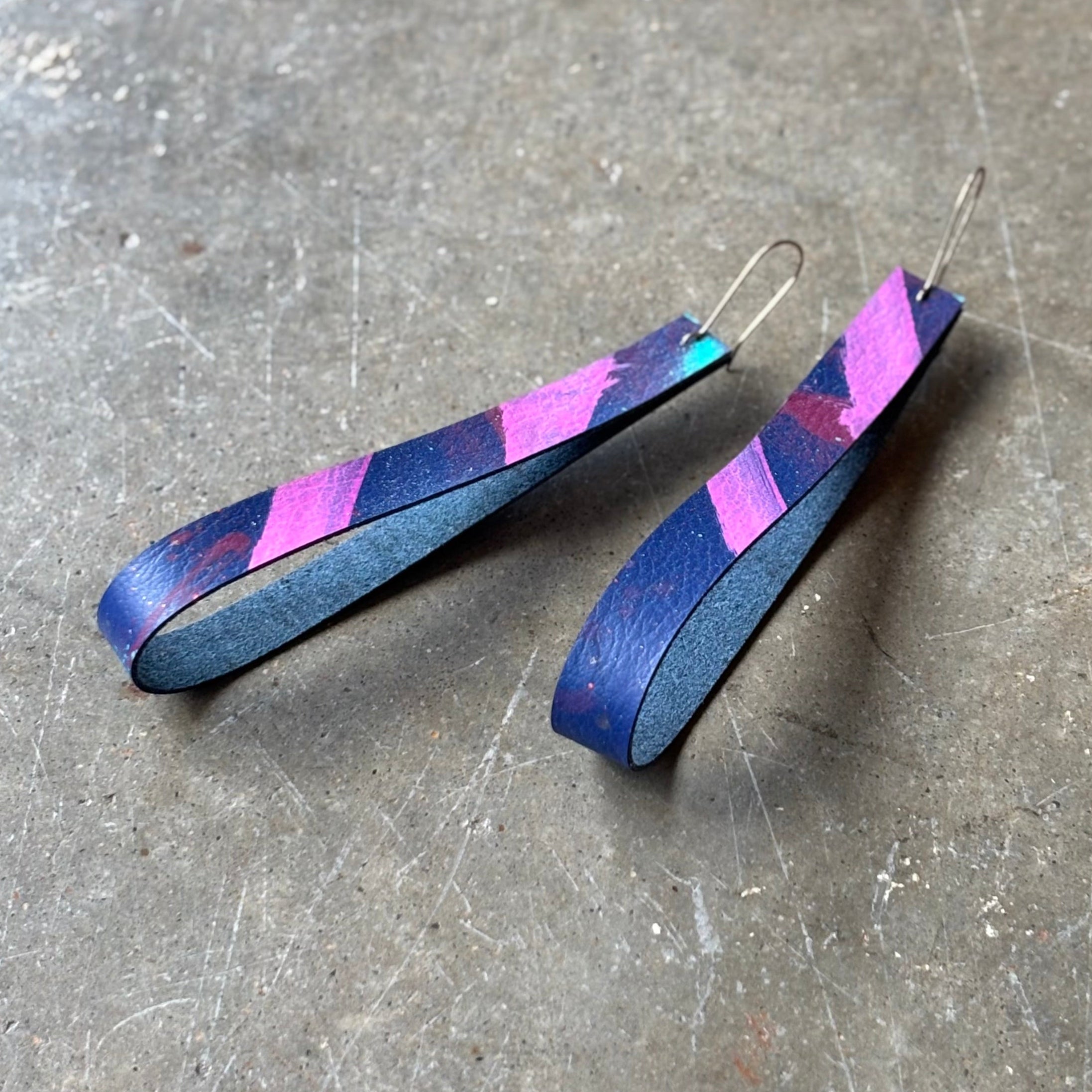 Pair of blue and pink striped earrings on a gray surface